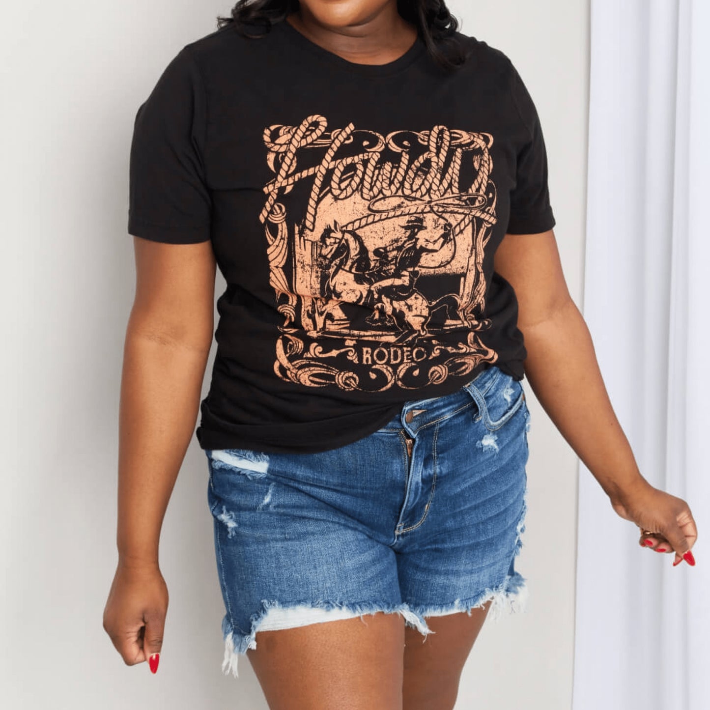 Lifestyle styling example of the black "Howdy" tee against a neutral background.