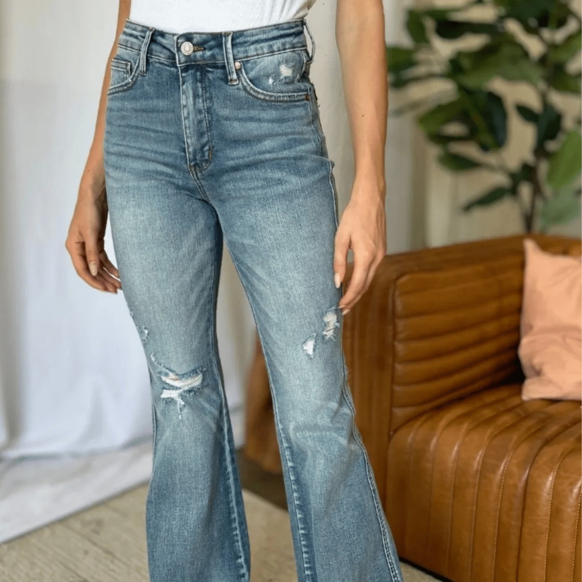 Front view of Judy Blue medium-rise tummy control flare jeans in a living room.
