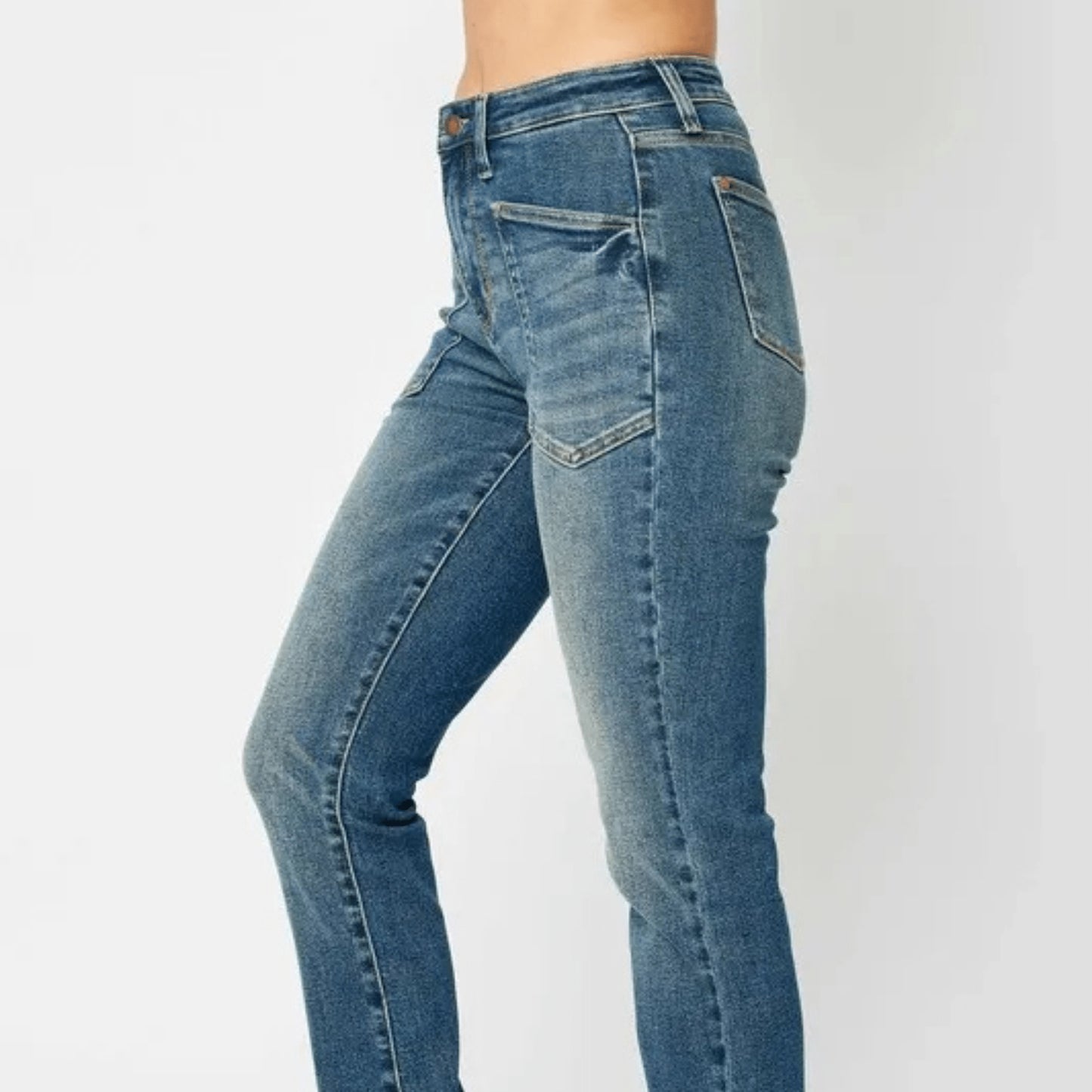 Side profile of dark wash skinny jeans paired with black sneakers.