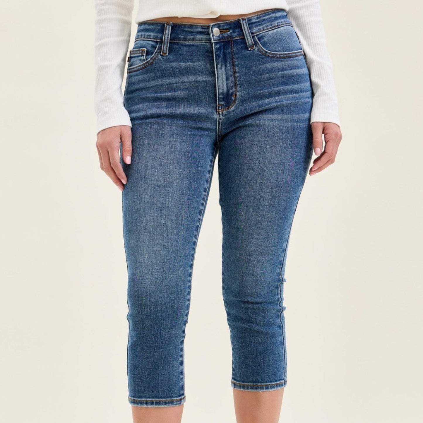 Woman wearing medium wash mid-rise stretch capri jeans with white sneakers.