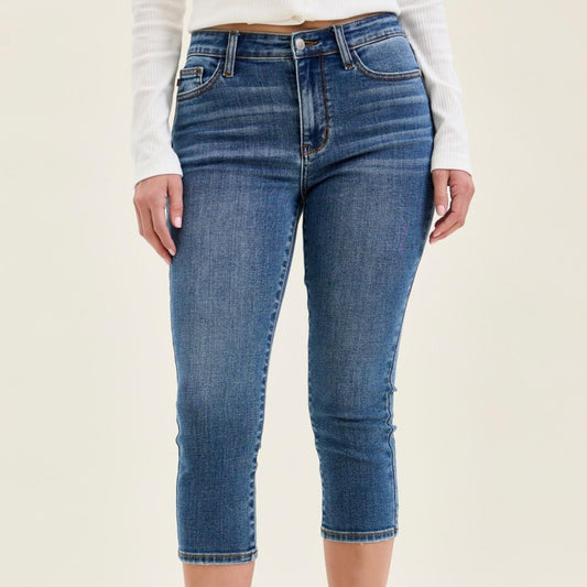 Woman wearing medium wash mid-rise stretch capri jeans with white sneakers.
