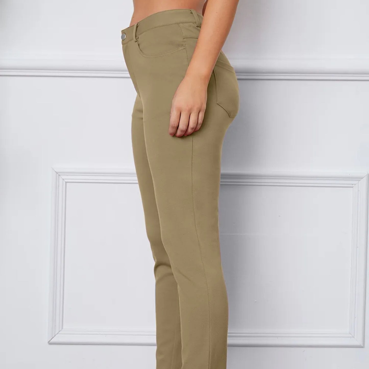 Khaki pants worn by a person against a white wall