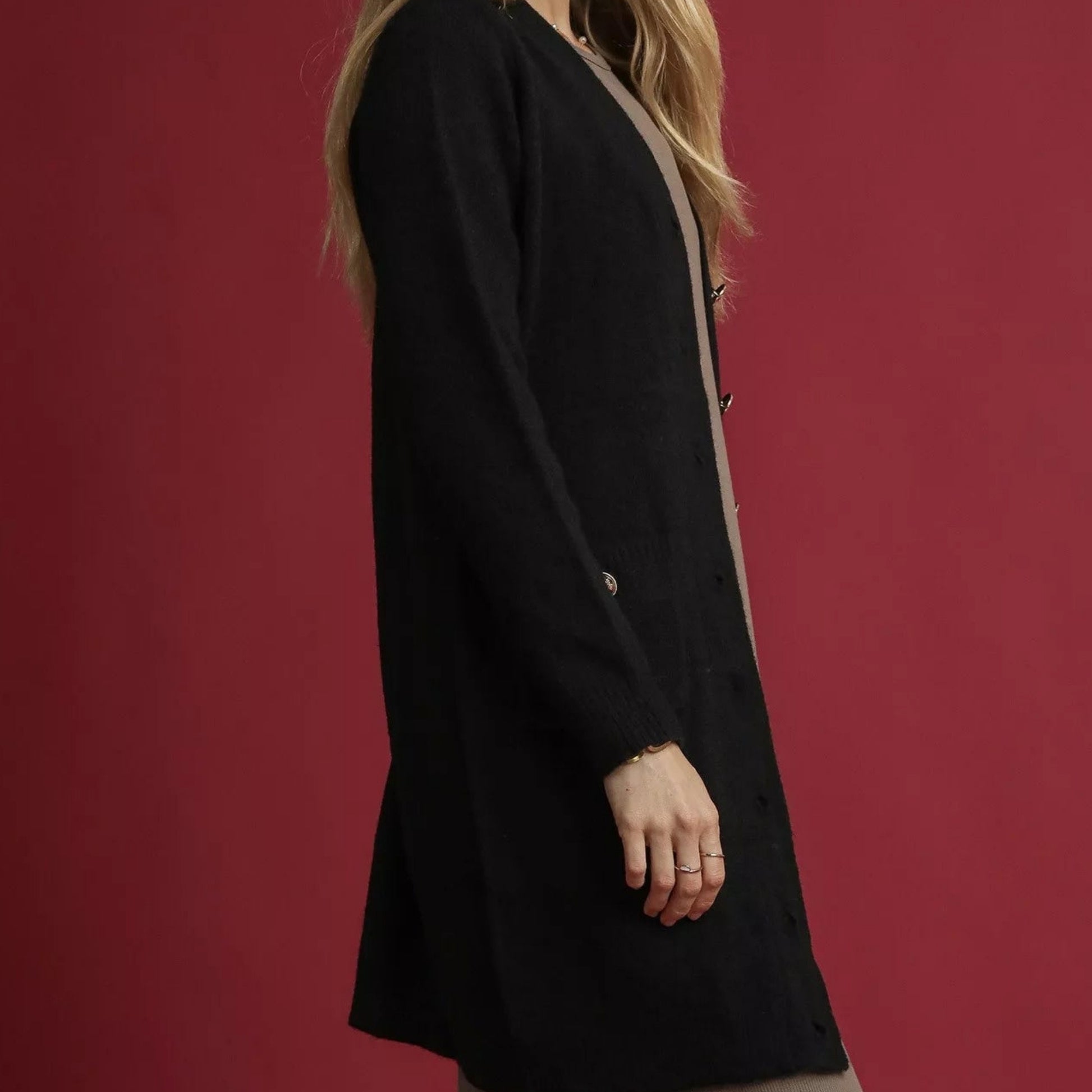 Person wearing a black coat against a red background