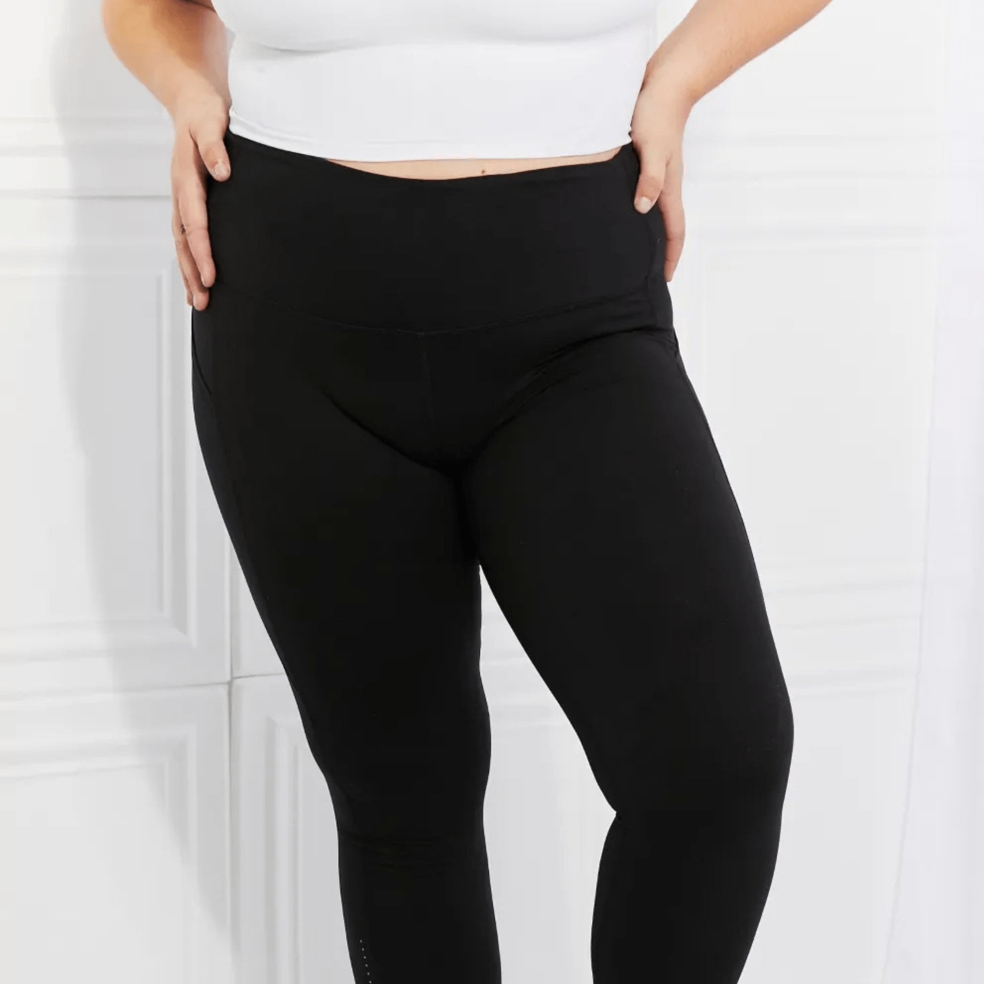 Action shot of a model wearing black reflective active leggings in a minimalistic setting.