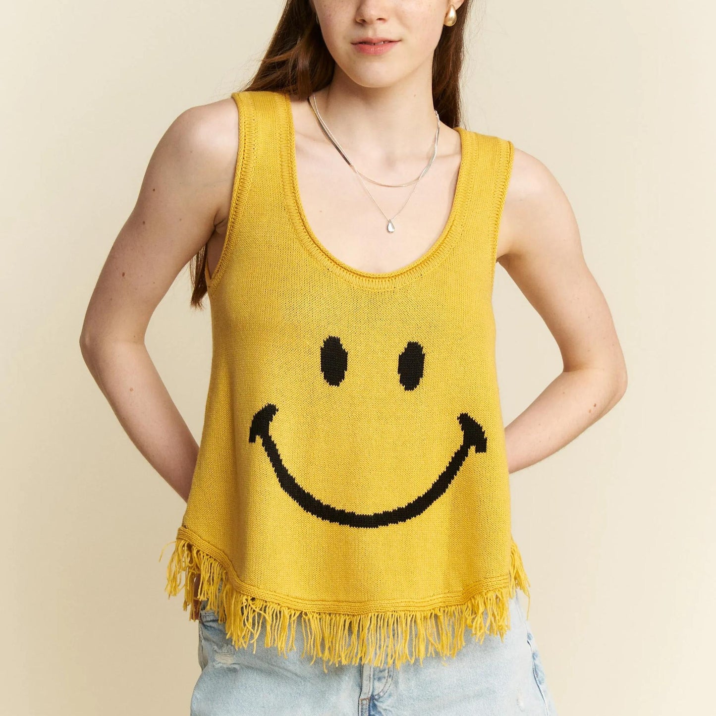 Close-up of the bold black smiley face graphic and boho fringe hem.