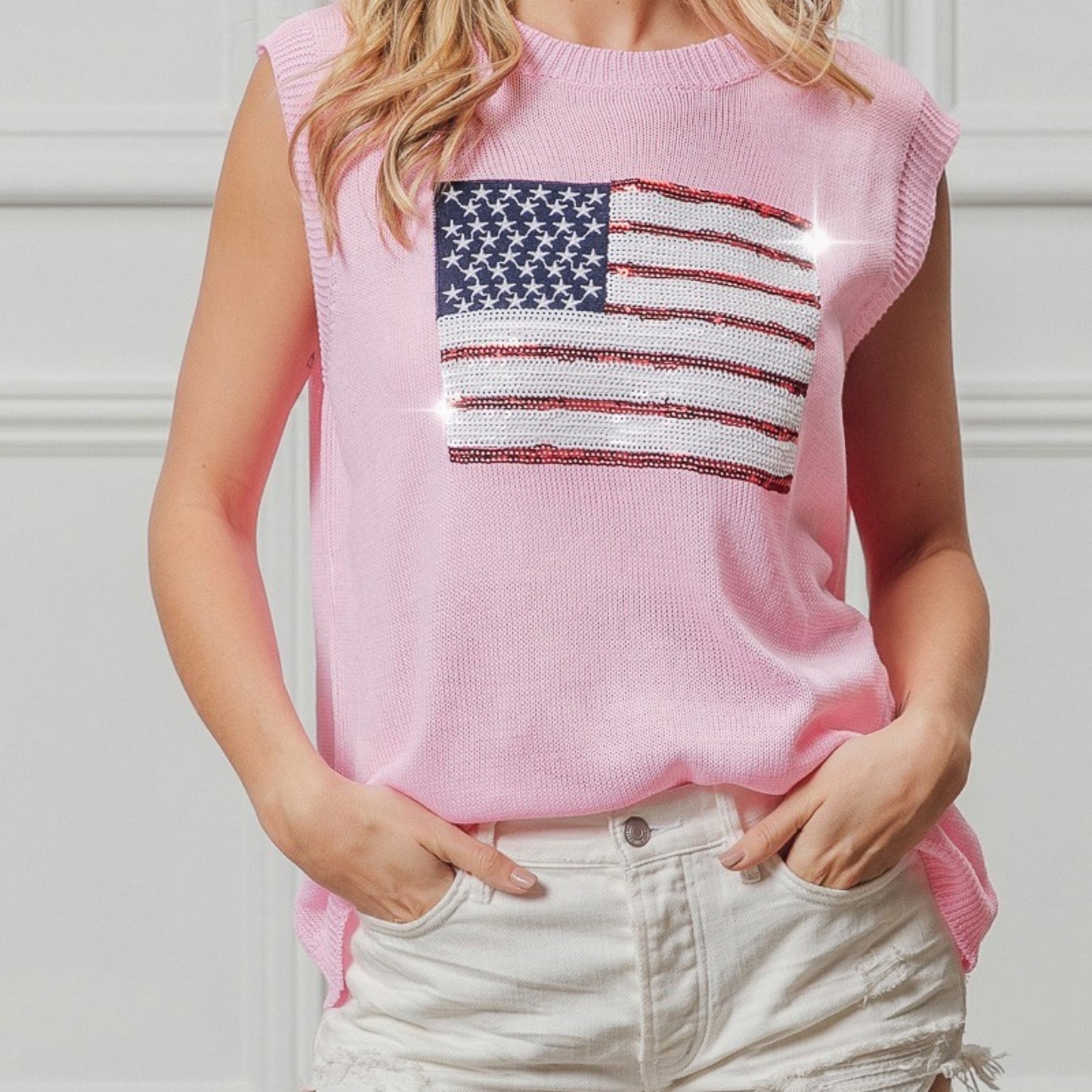 Person wearing a pink sleeveless top with an American flag design against a neutral background