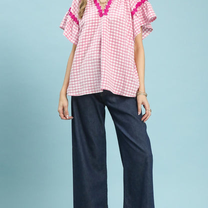 Lifestyle view of the Umgee Peony gingham top paired with white denim.
