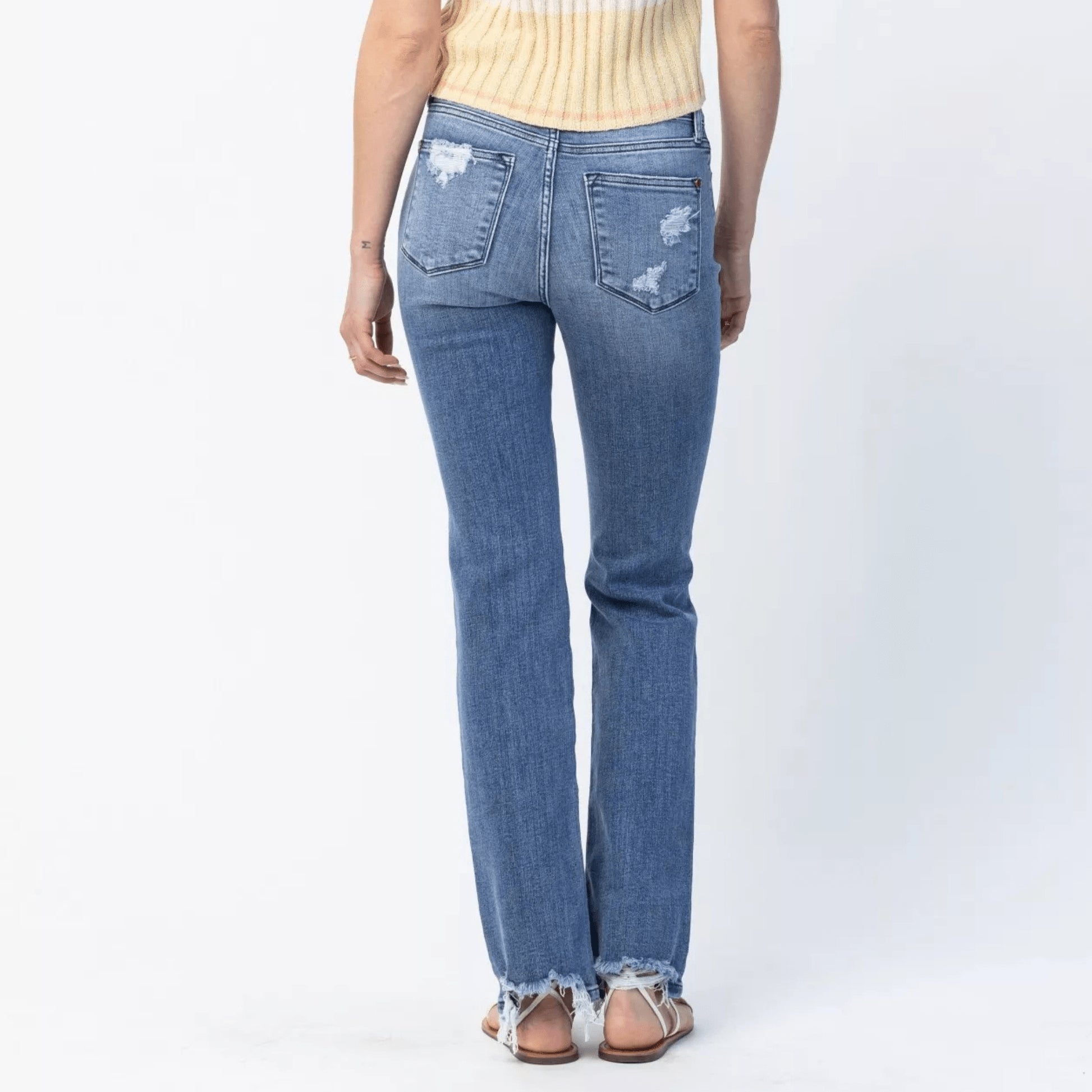 Back view of medium wash straight leg jeans with distressed detailing.
