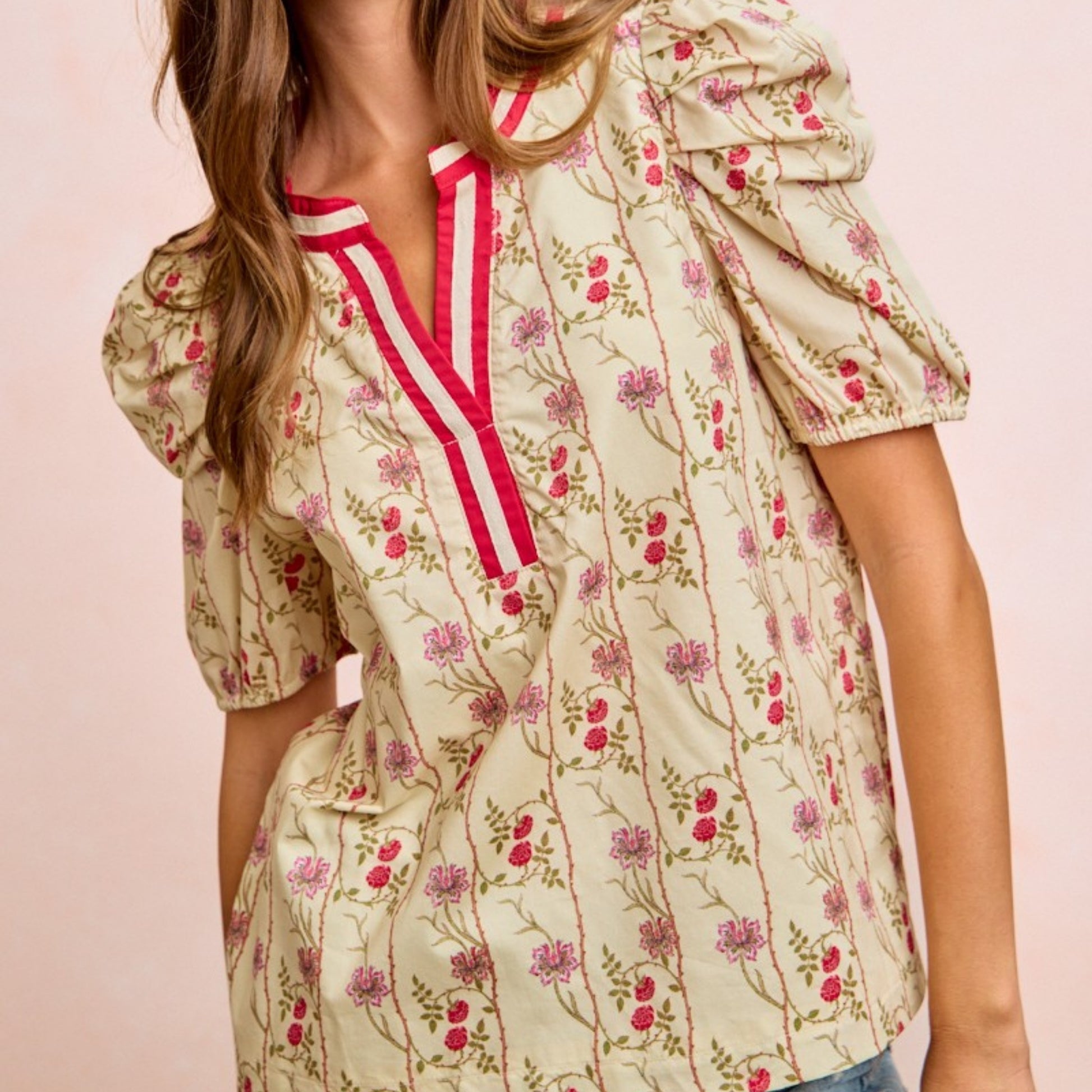 Woman wearing a floral blouse with red accents on a pink background