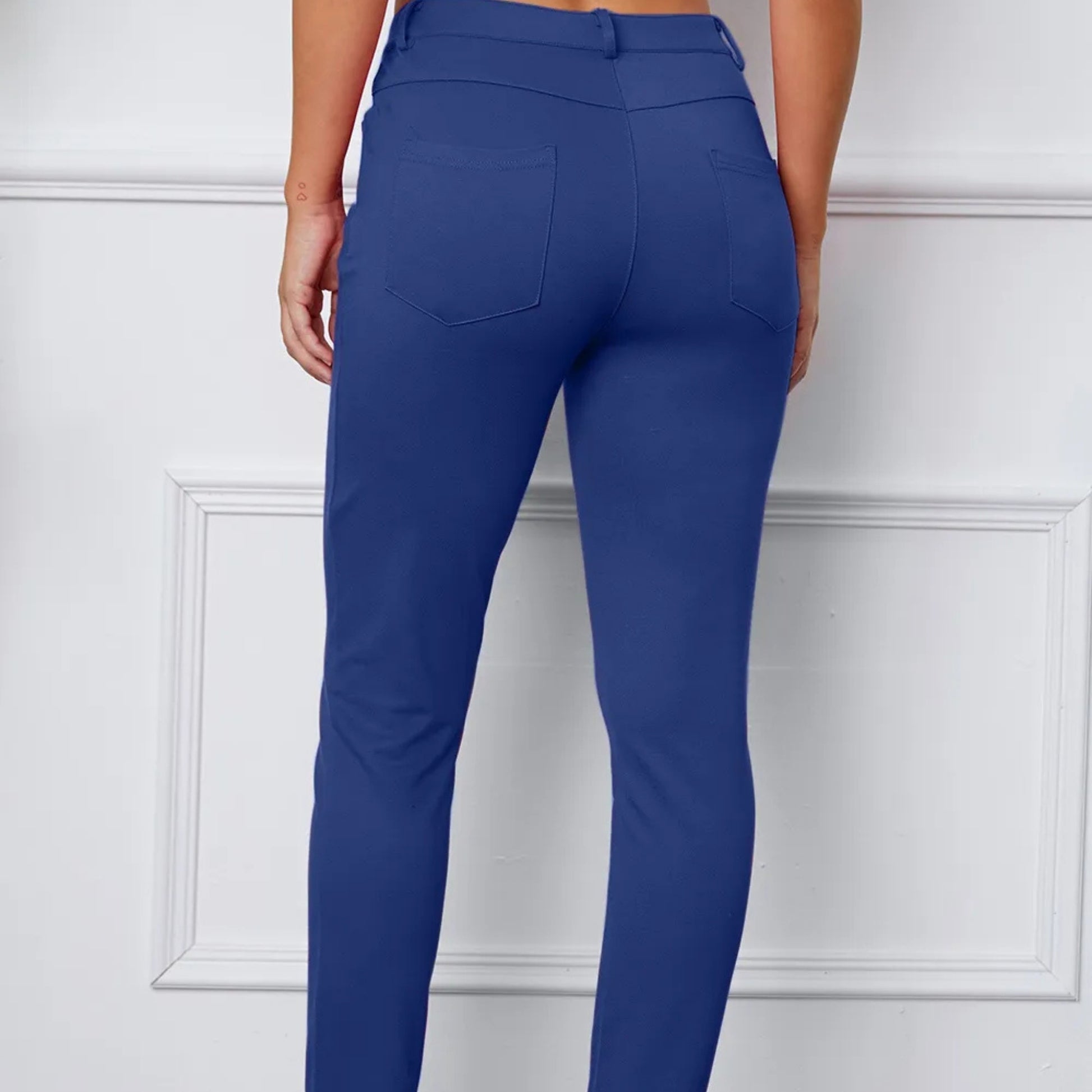 Royal Blue pants worn by a person on a white paneled wall background