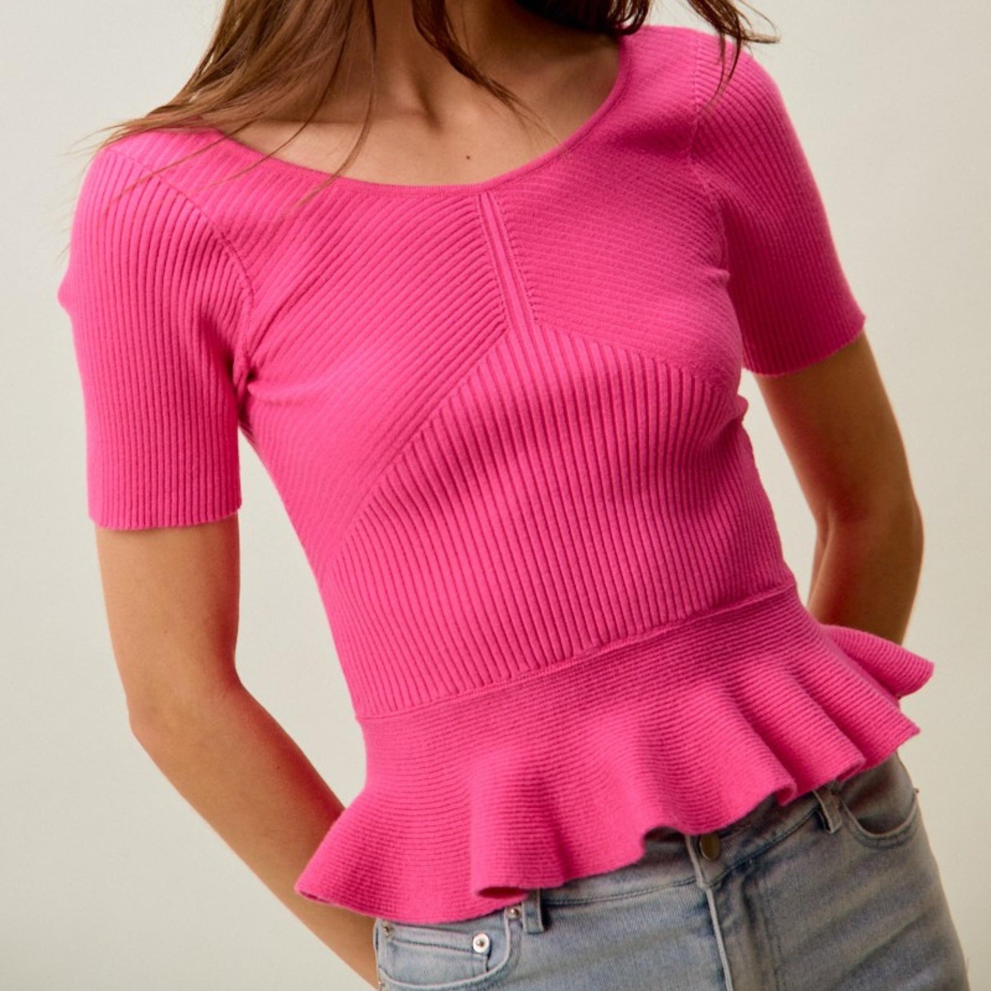 Close-up of the SO ME hot pink ribbed knit texture and peplum hem.