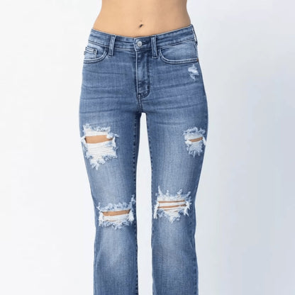 Model shot of Judy Blue straight leg distressed denim with a raw hem.