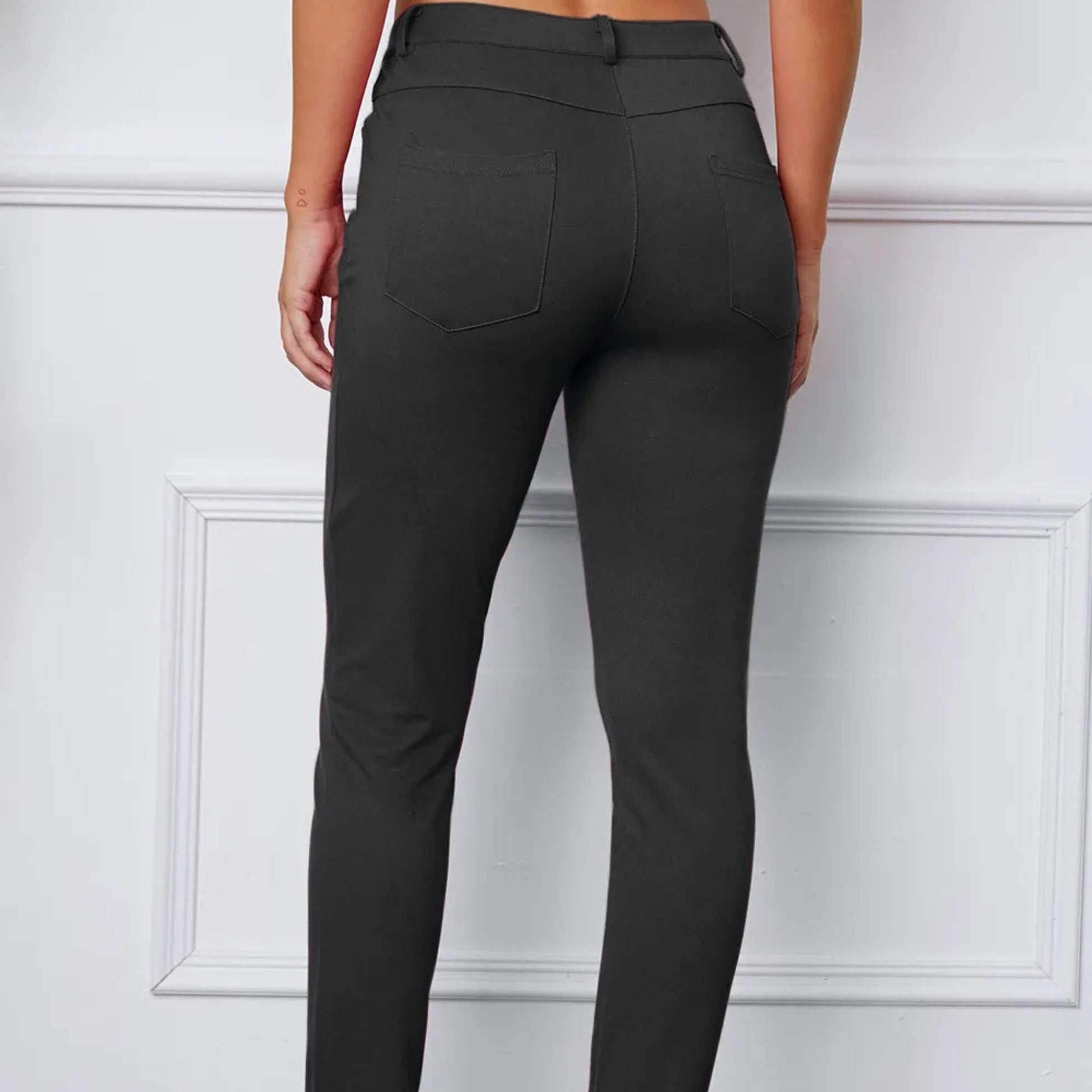 Dark grey pants worn by a person on a white paneled background