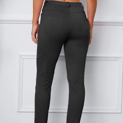 Dark grey pants worn by a person on a white paneled background