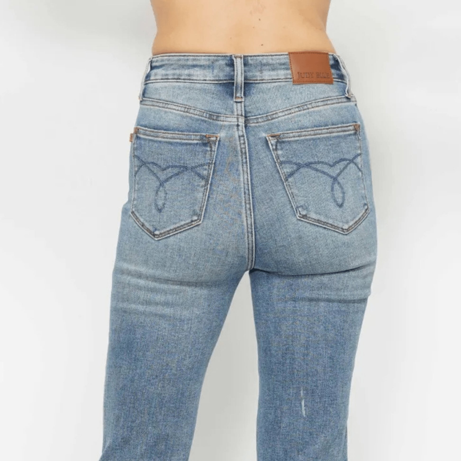 Close-up showing the stretch and texture of the medium wash embroidered denim.