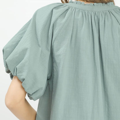 Close-up of the intricate lace inset and romantic puff sleeve design on the cotton blouse.
