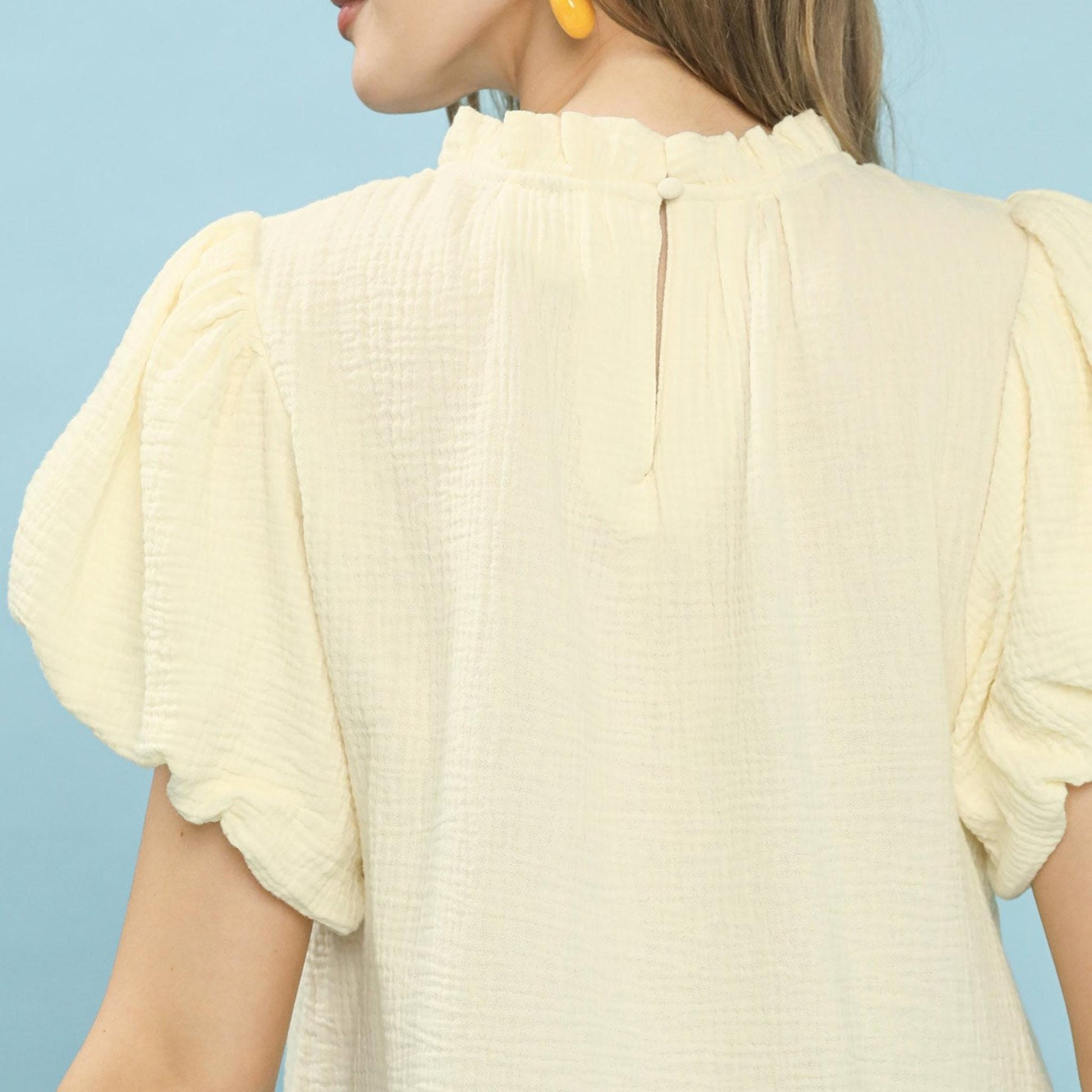Close-up of the ruffle neckline and tassel ties on the Umgee Cream gauze top.