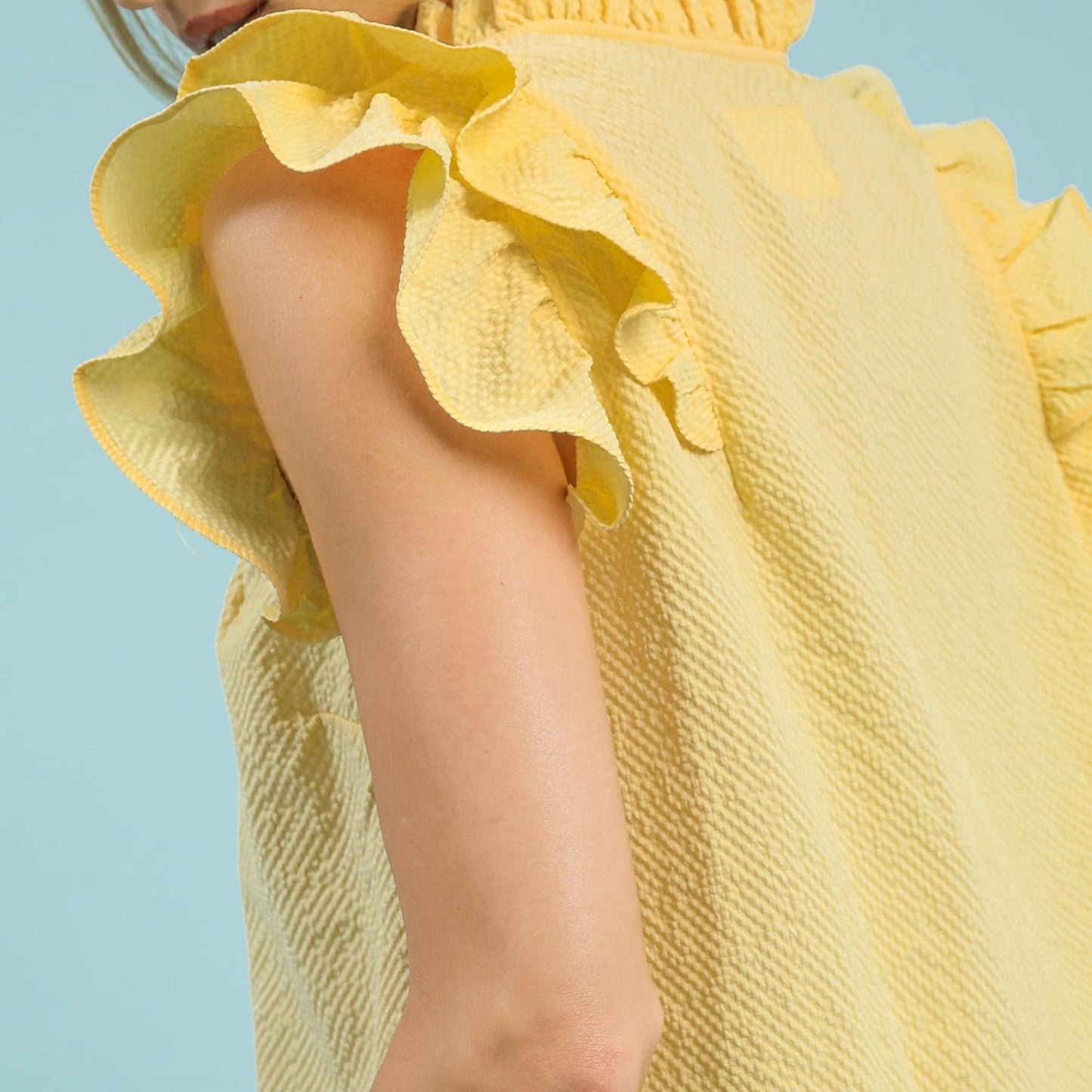 Close-up view highlighting the intricate textured fabric and ruffle sleeve design.