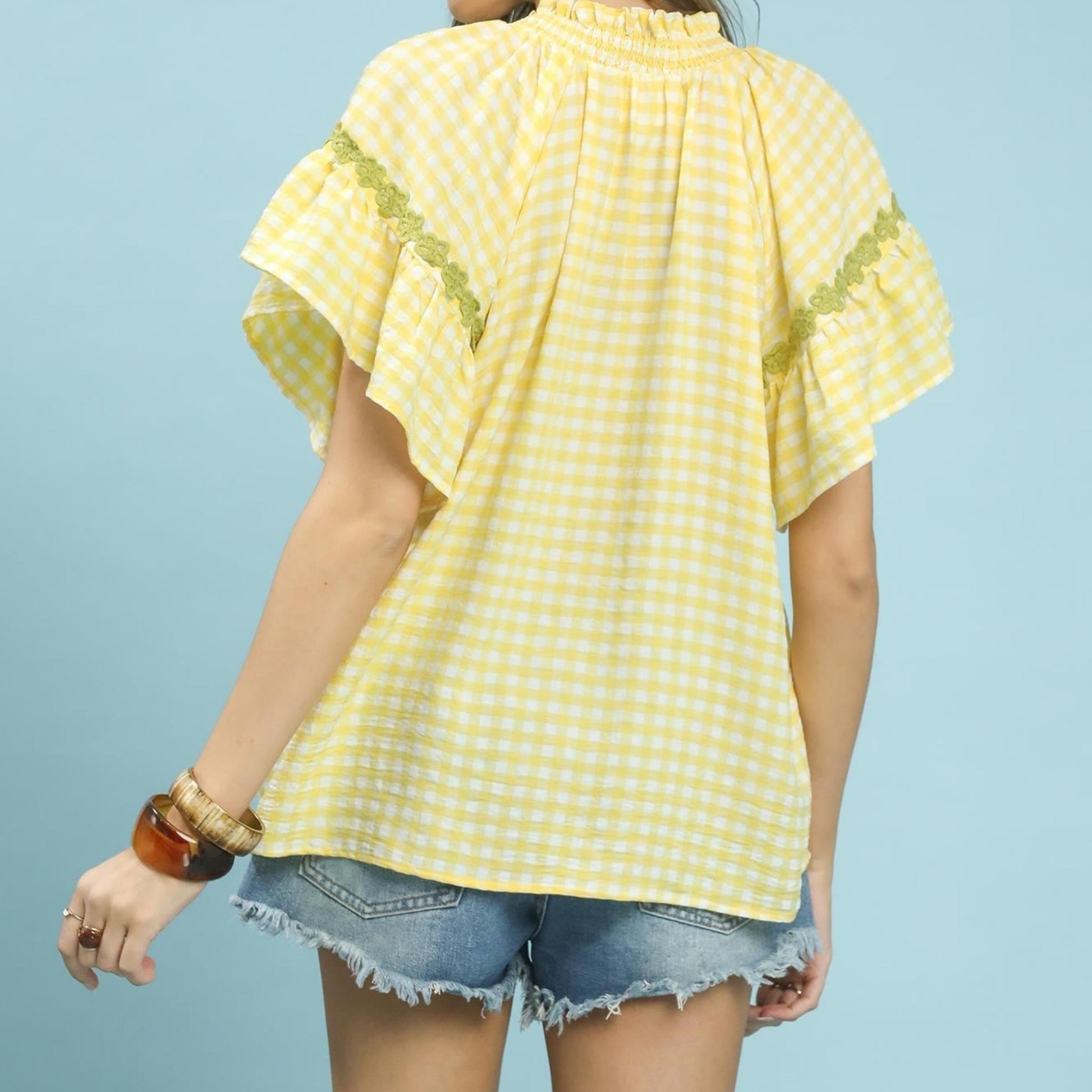 Flat lay view of the Umgee lemon gingham lace trim top with casual styling.