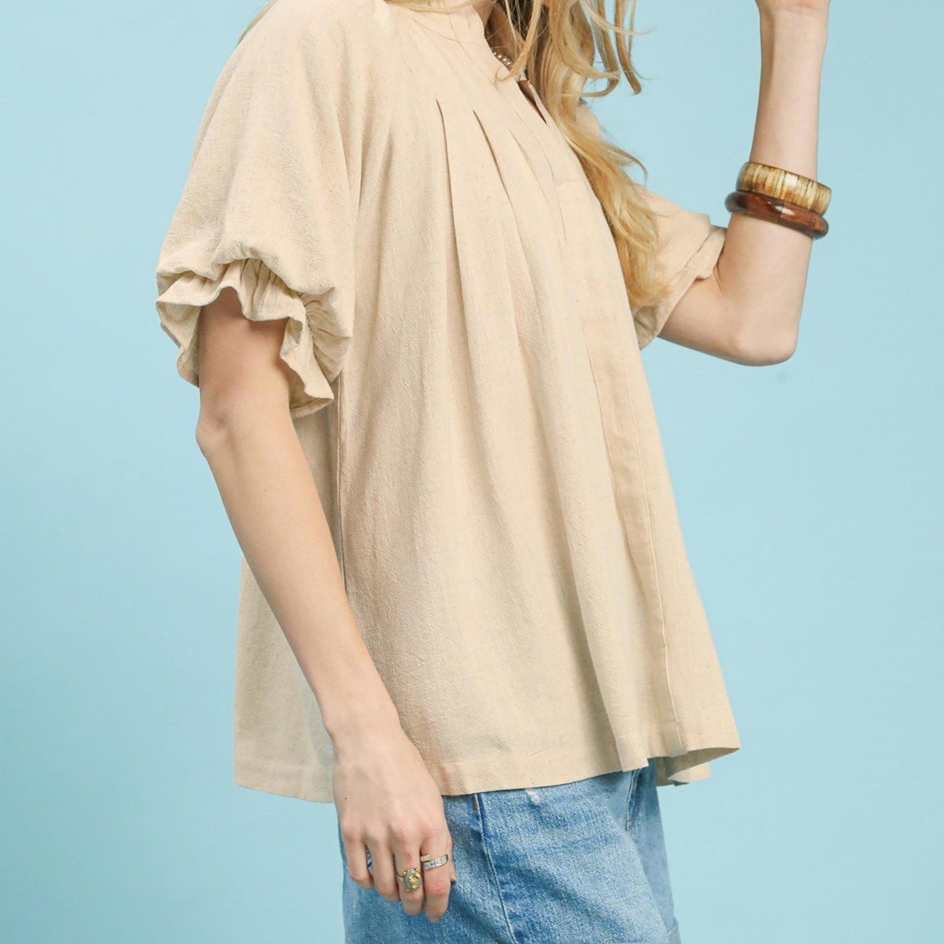 Side view of the Umgee oatmeal linen top showing the delicate pleated detailing.