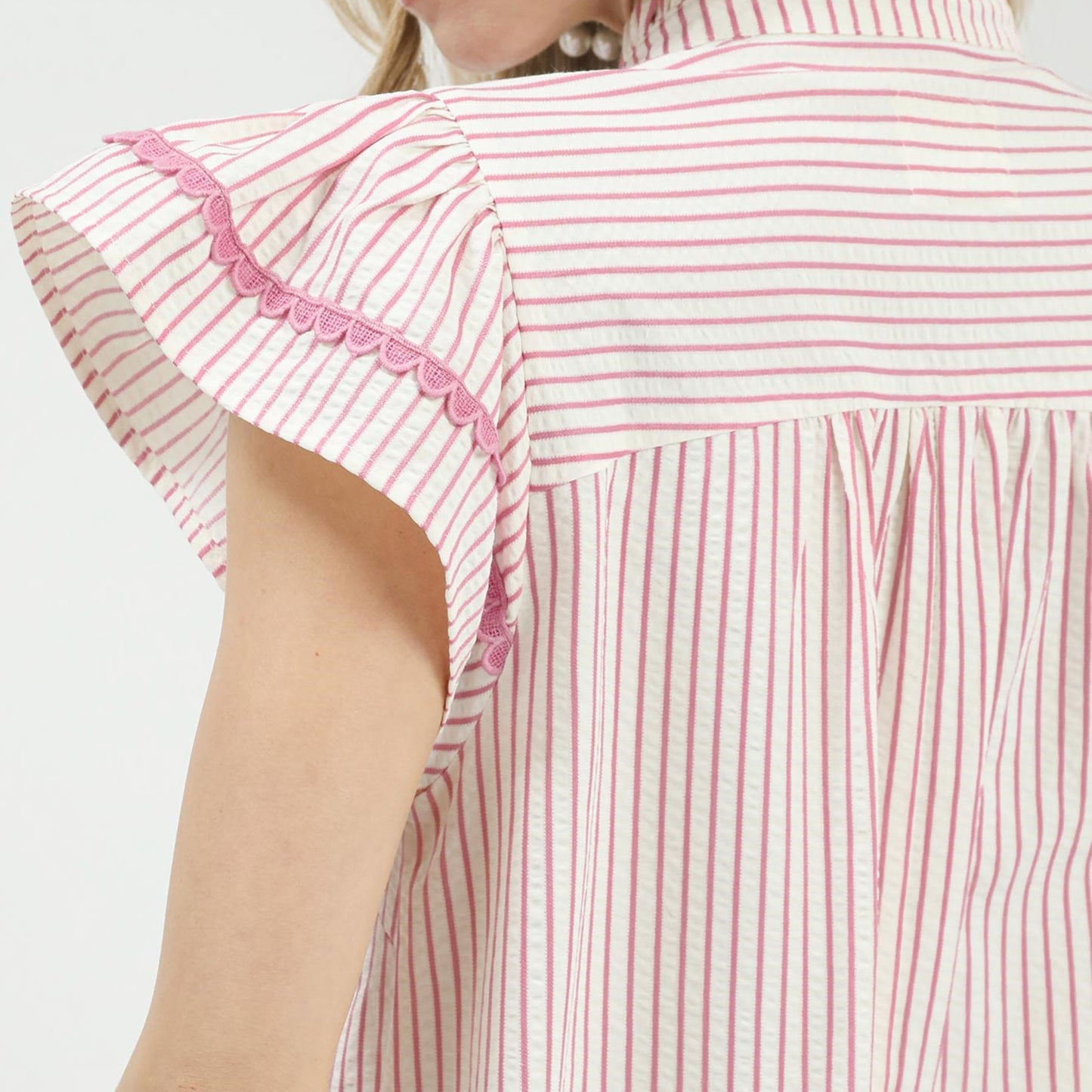 Close-up of the delicate lace and ruffled detailing on the pink striped top.