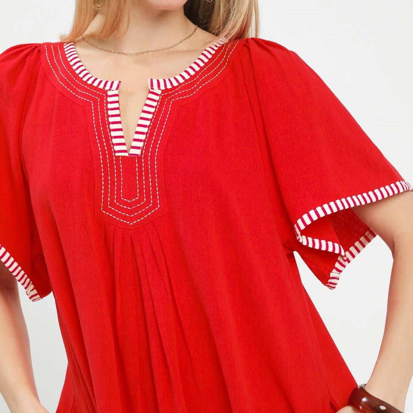 Close-up of the modern split V-neck and pleated detailing on the red linen-blend tunic.