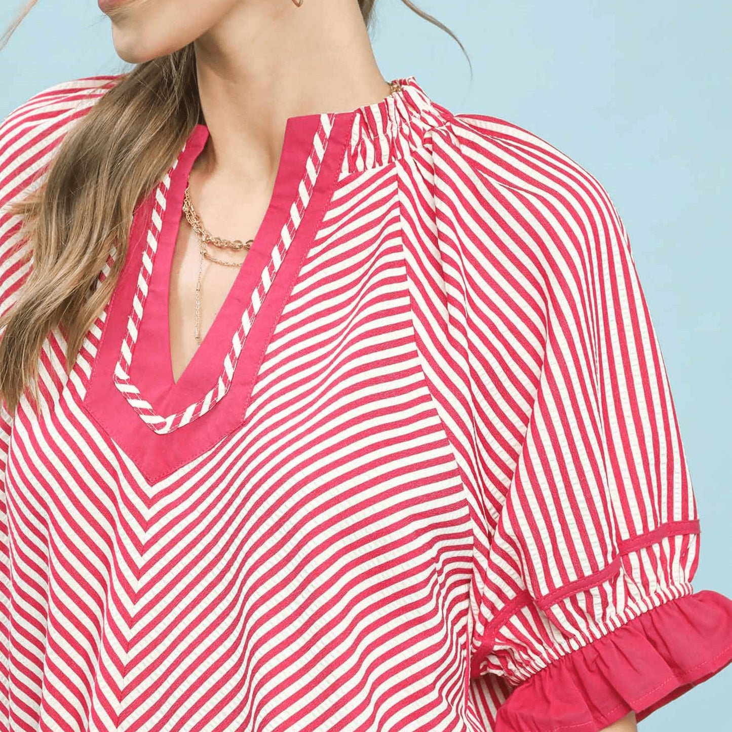 Detailed view of the feminine ruffle sleeves on the raspberry striped blouse.