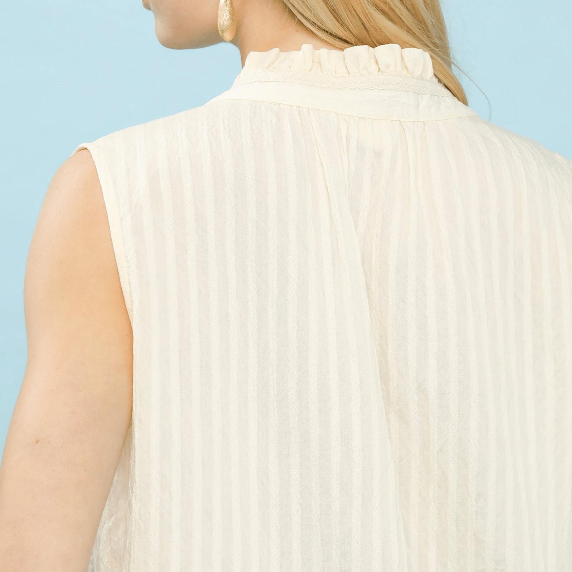 Close-up of the split-neckline and textured gauze fabric on the sleeveless top.