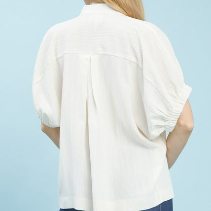 Back view of the women's cream textured blouse highlighting the flowy fit.
