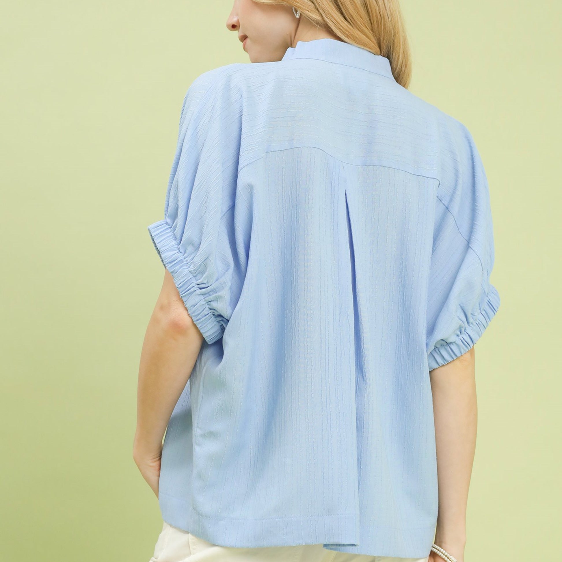 Back view of the women's light blue textured blouse highlighting the sleek finish.