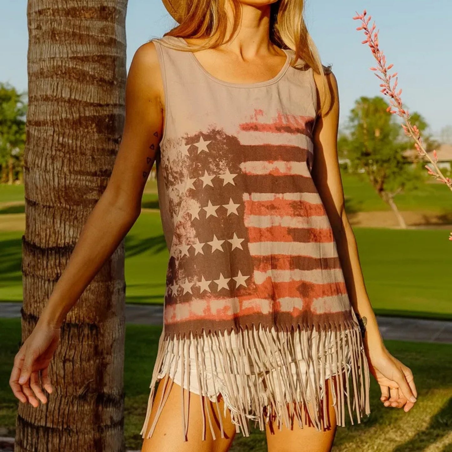 Woman wearing a tank top with an American flag design in a park setting