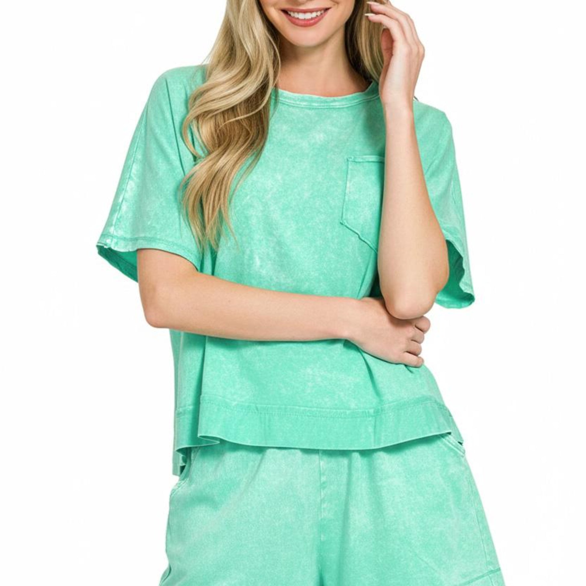 Woman wearing a mint green outfit with a top and shorts on a white background